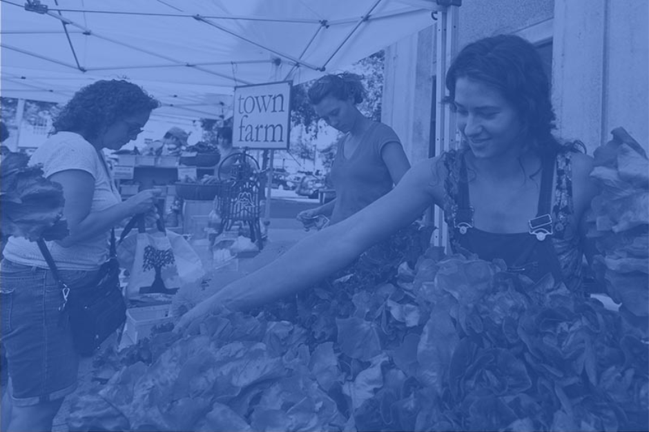 woman extending her arm over a pile of lettuce