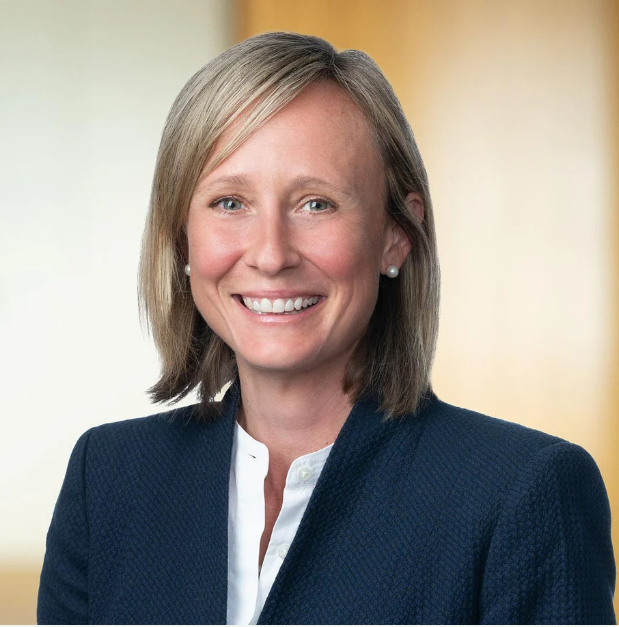 Photo of attorney Christina Licursi. Light-skinned woman with shoulder-length blonde-grey hair. She wears a dark blue blazer, white buttoned shirt, and she is smiling at the camera.